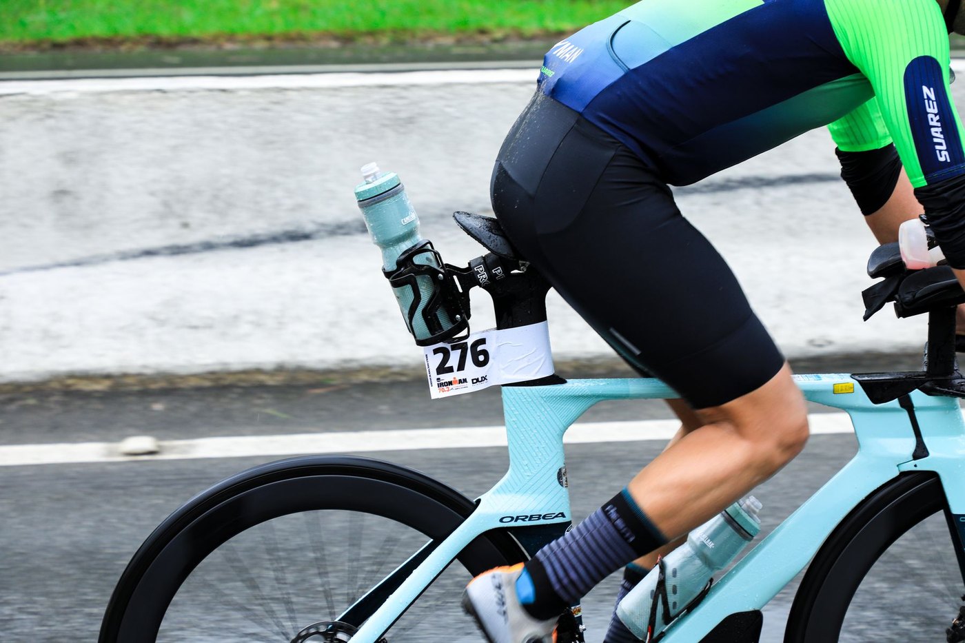 Triathlète roulant avec casque, dossard et hydratation avant la transition vers la course à pied