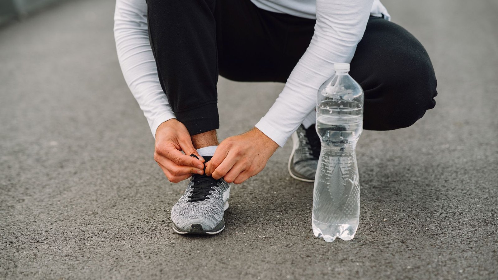 Coureur nouant ses chaussures avec une gourde à côté avant une séance de course