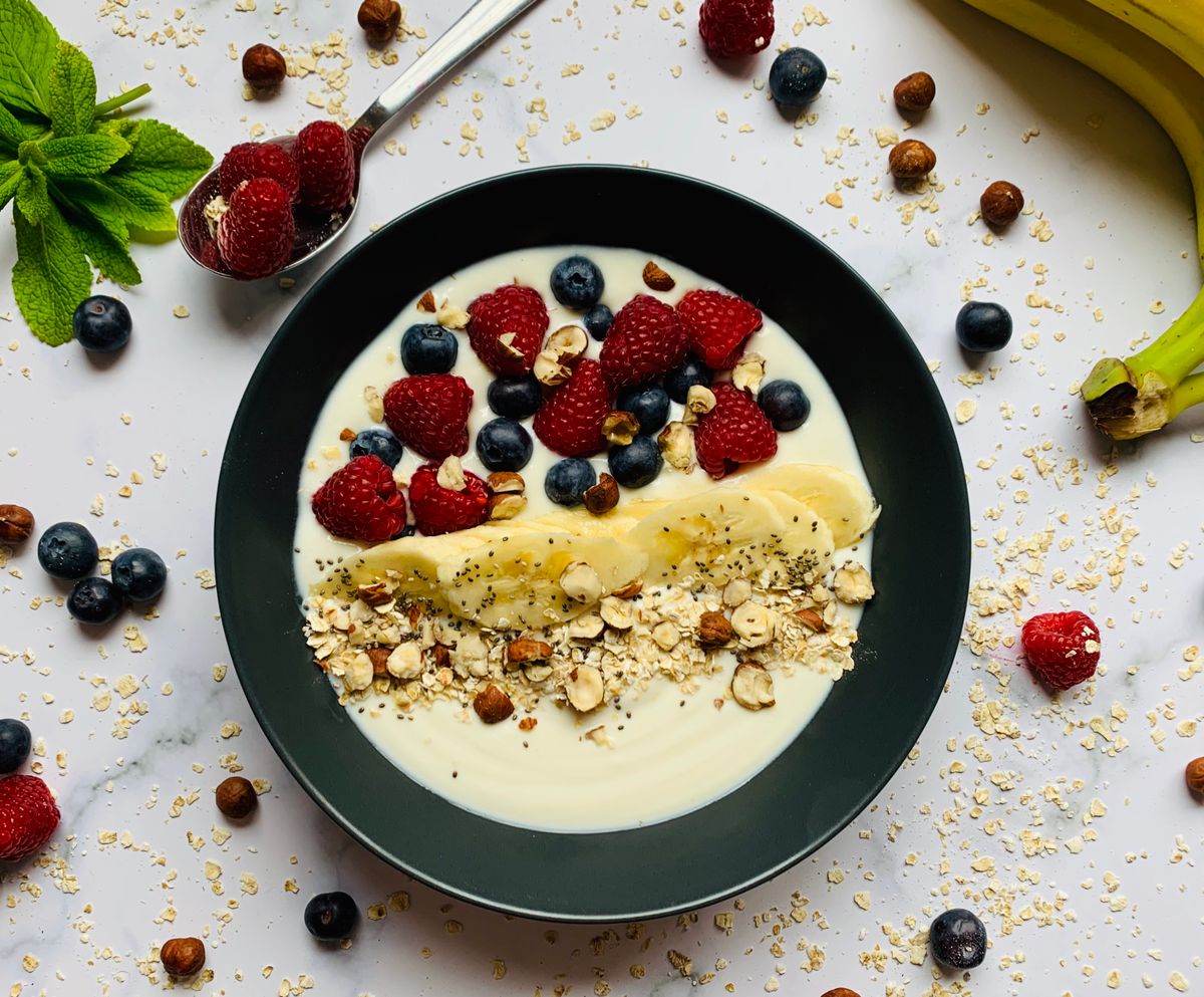 Bol de petit-déjeuner avec céréales, fruits, graines et produit laitier ou alternative