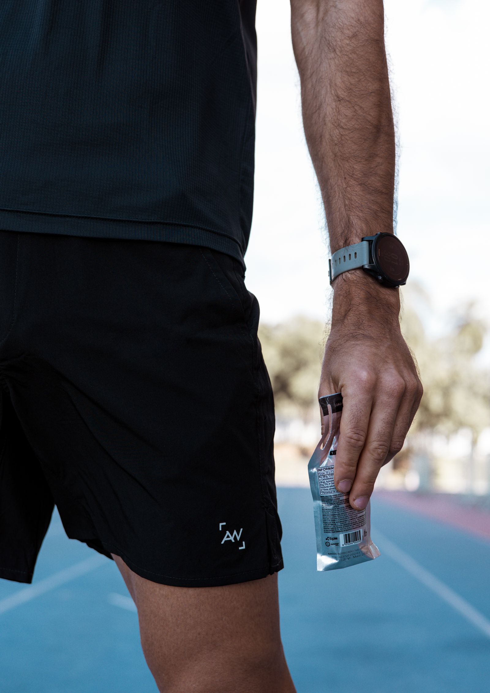 Coureur tenant un gel énergétique sur une piste d'athlétisme